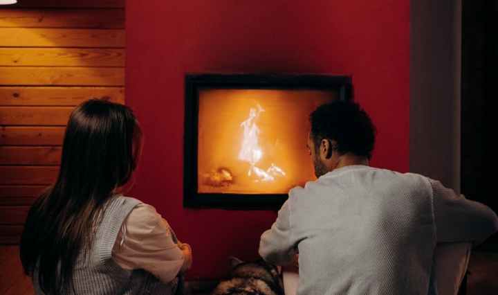 couple sitting near fireplace with their dog