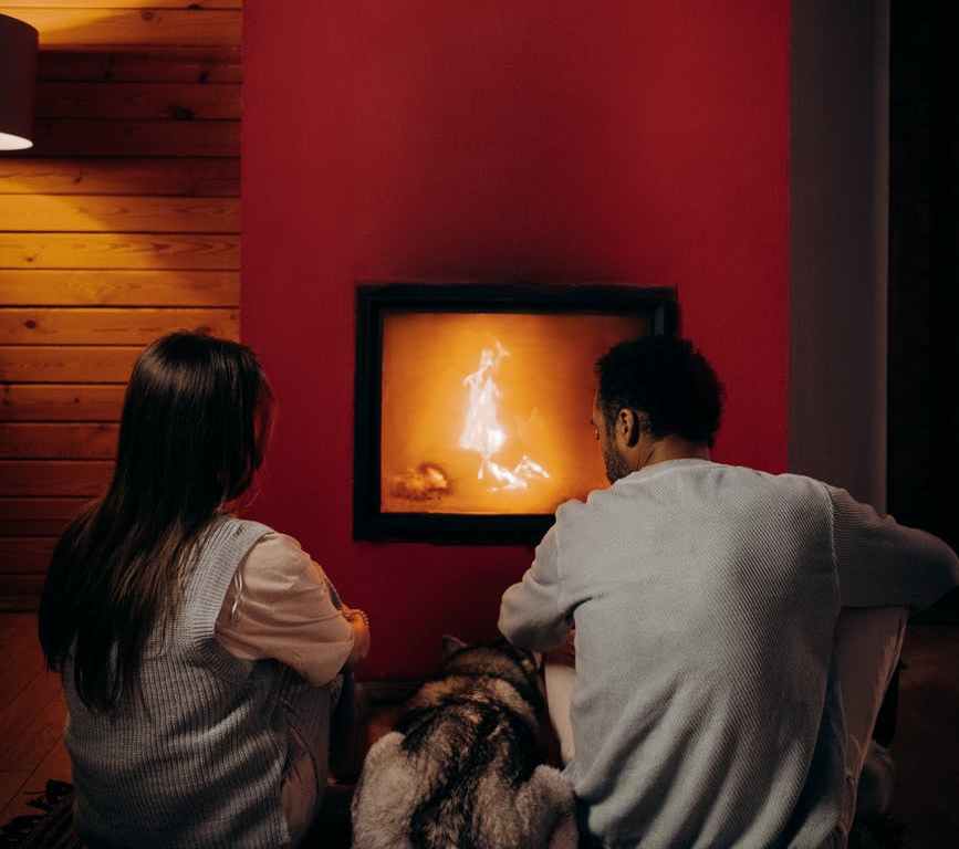 couple sitting near fireplace with their dog